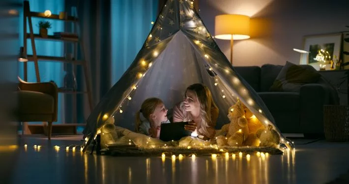 Mother and daughter play in an indoor teepee tent.