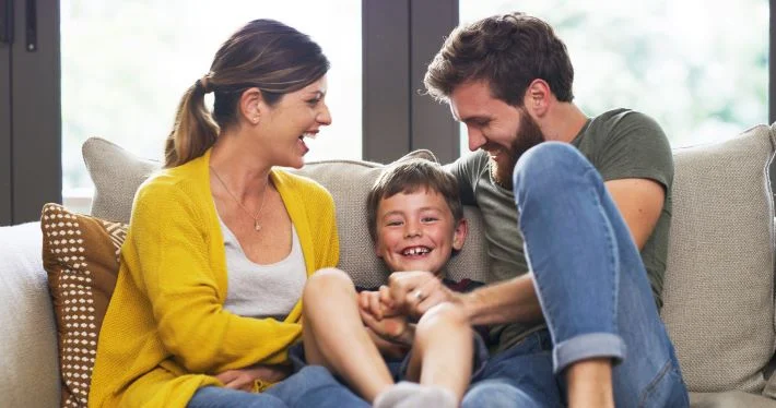 Smiling family on a living room lounge sofa spending quality time together at home.