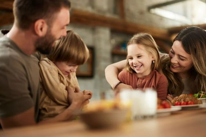 Happy parents spending time with their small children at breakfast.