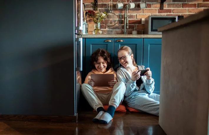 Teenage children using mobile devices in their international home.