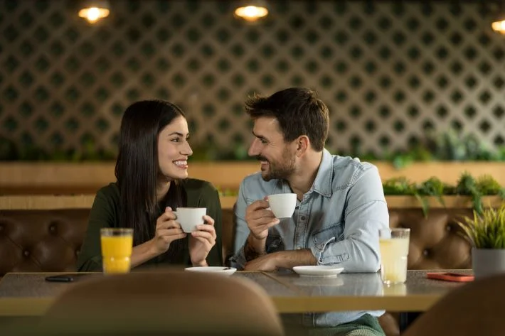 A couple talking and enjoying coffee together.