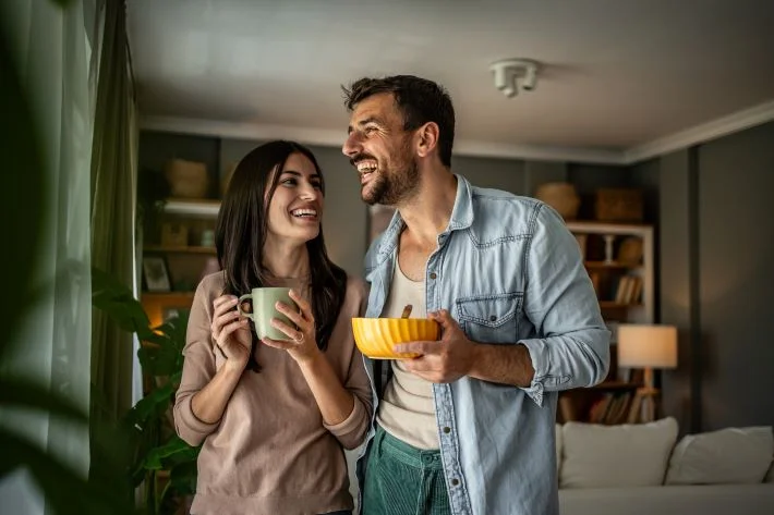 A smiling couple enjoying breakfast at home.