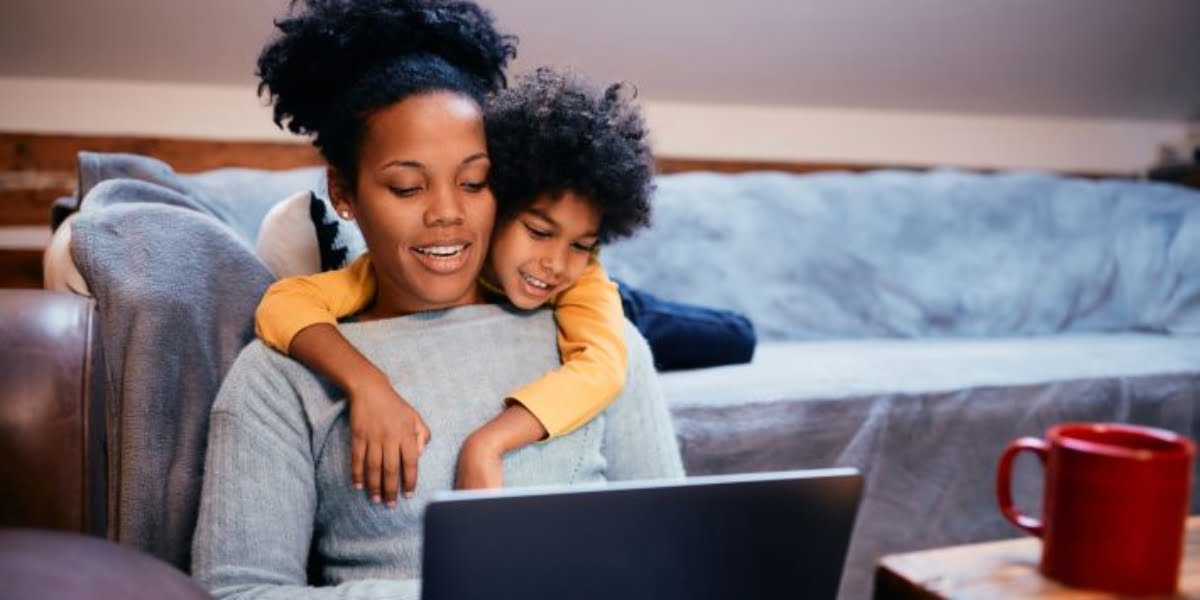 Happy mother and daughter surfing the net on laptop while relaxing at home.