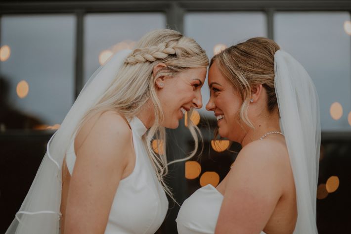 Two women holding hands and celebrating at their LGBTQI+ wedding.