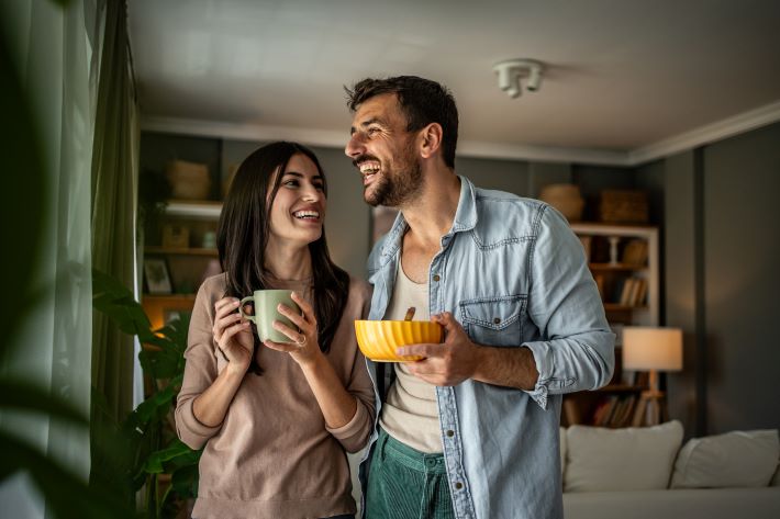 A smiling couple enjoying breakfast at home.