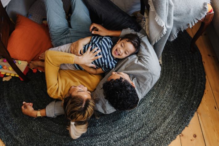 An overhead view of a little boy having fun with his mum and dad at home.
