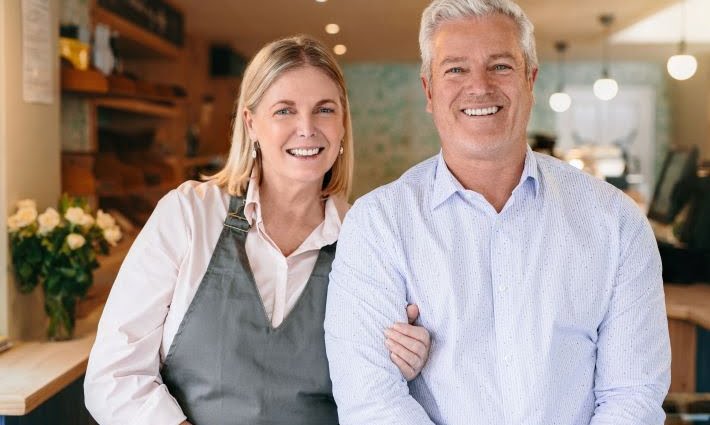 Couple standing arm in arm in their self-owned coffee shop