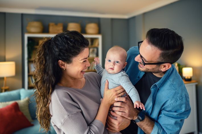 Happy young parents playing with their baby girl at home.