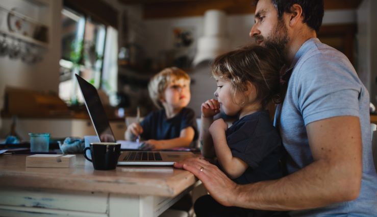 Father with small children playing on laptop at home.