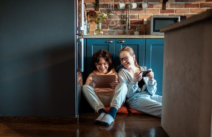 Teenage children using mobile devices in their international home.