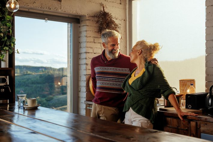 A smiling couple enjoy talking in the kitchen.