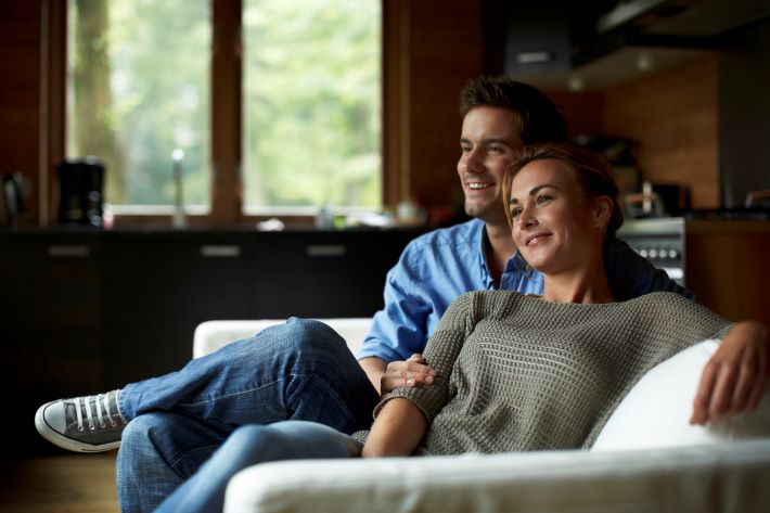 A smiling couple looking relaxed on the sofa.