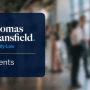 A group of people smiling and talking together in hall, with a blue overlay on the left showing Thomas Mansfield Family Law Events.